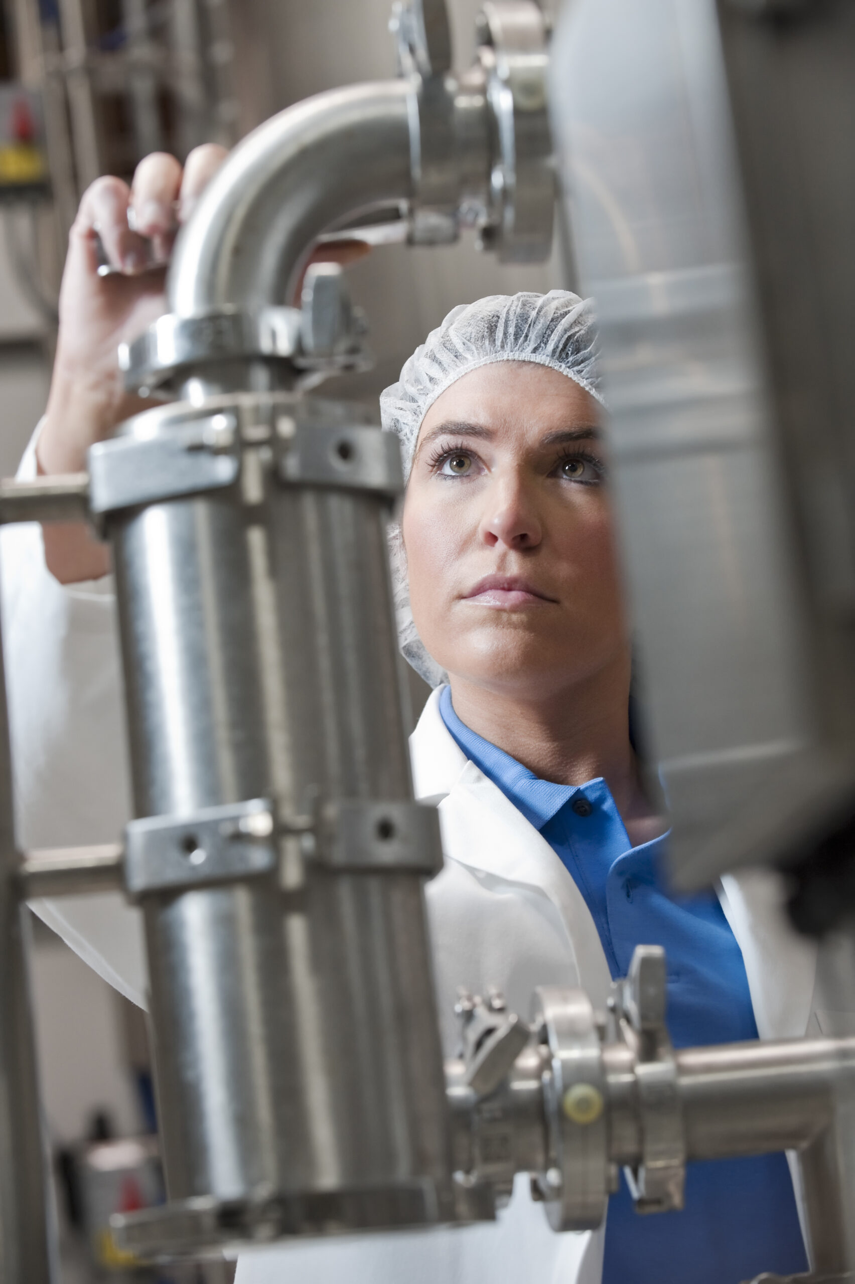 Lebensmittel Chemikerin in weißem Kittel und Haarnetz kontrolliert einen Edelstahltank in einem Abfüllwerk